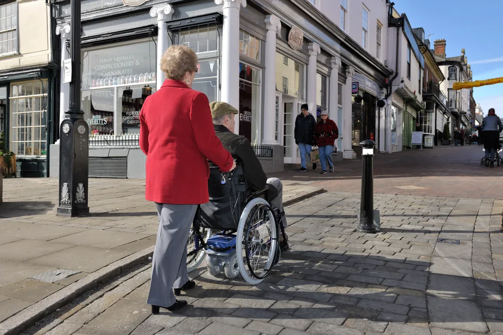 Acompañante empujando una silla de ruedas con motor TGA Powerpack por la calle