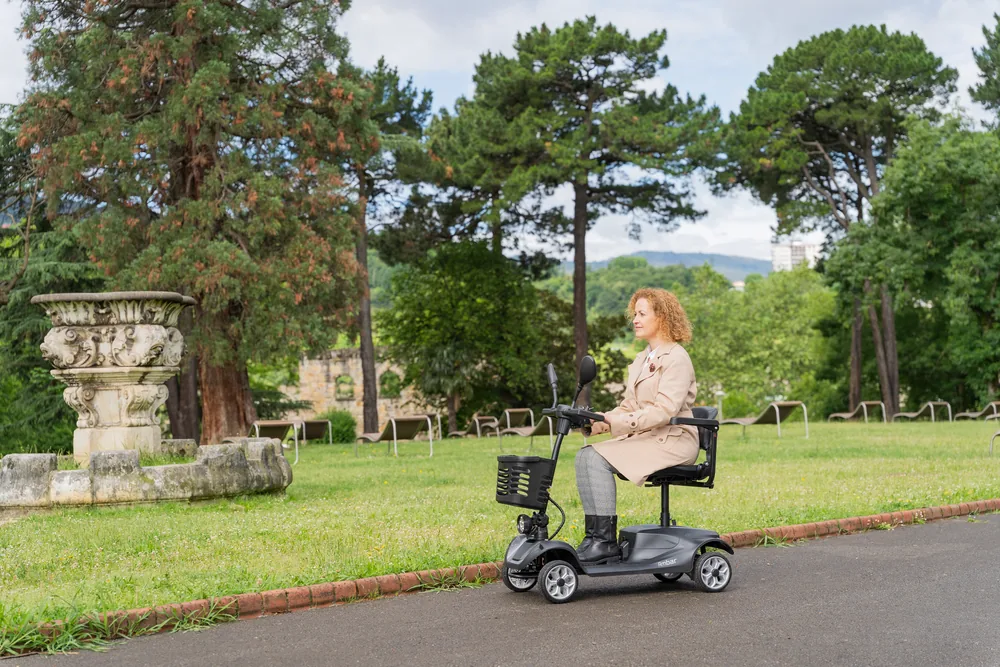 Mujer conduciendo el scooter eléctrico Ambar de Wellell en un parque