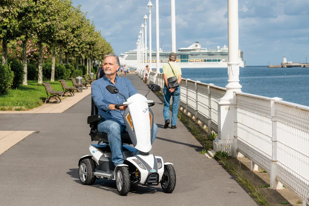 Hombre en el scooter eléctrico I-Vita de Wellell por un paseo marítimo