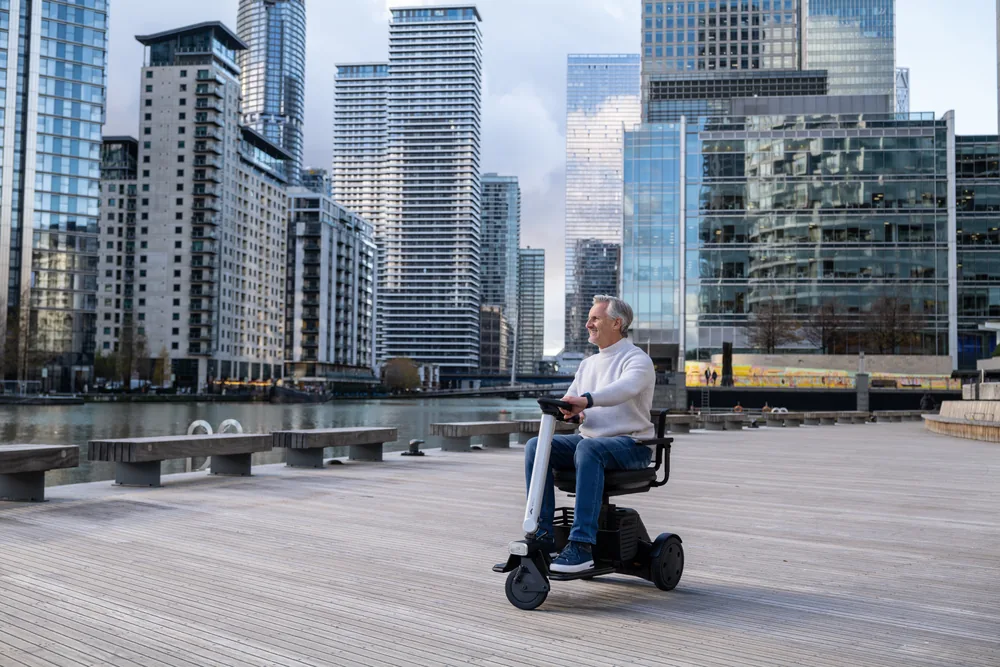 Hombre conduciendo el scooter WHILL Model R de 3 ruedas entre rascacielos