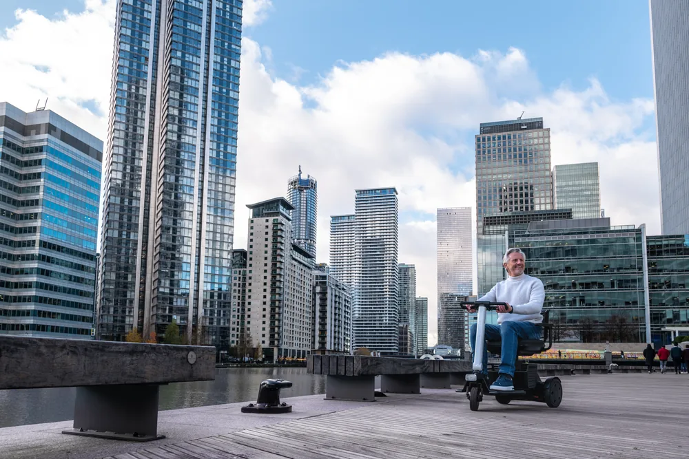 Hombre en el scooter WHILL Model R de 3 ruedas en un muelle urbano