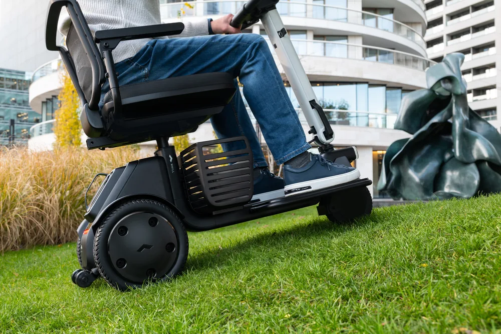 Scooter WHILL Model R de 3 ruedas circulando sobre césped
