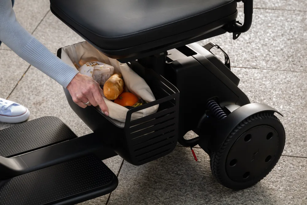 Cesta bajo el asiento del scooter WHILL Model R de 3 ruedas con la compra