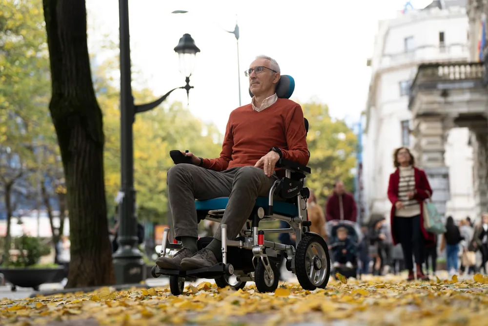 Hombre en la silla de ruedas eléctrica I-Discover 2 por un paseo en otoño