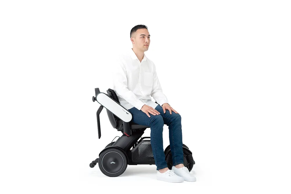 Hombre sentado en la silla de ruedas eléctrica WHILL Model C2